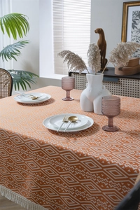 Detalle del mantel jacquard naranja con patrón de diamantes geométricos y flecos blancos