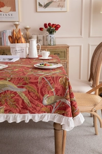 Detail of red floral cotton canvas tablecloth with white ruffled edges and bird prints
