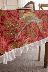 Detail of red vintage canvas tablecloth with floral pheasant print and ruffled white edges
