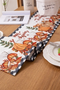 Detail of Happy Thanksgiving table runner with pumpkin motif and black white plaid edges