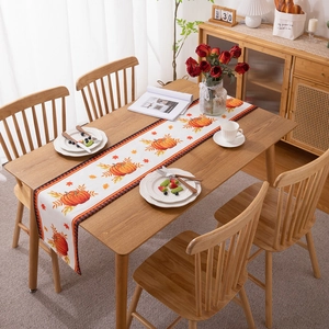 Thanksgiving pumpkin and maple leaf table runner with gingham border on wooden dining table