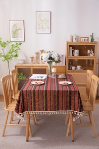 Detail of bohemian striped tablecloth with white tassels on a rustic wooden table
