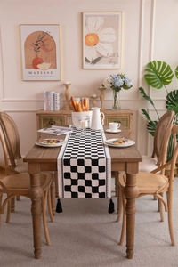 Close-up of black and white checkerboard table runner with cotton thread tassels
