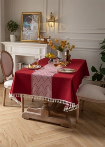 Detalle de mantel de jacquard rojo con patrones geométricos blancos y bordes de borlas