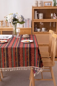 Detail of bohemian colorful striped tablecloth with fringe tassels on a wooden table