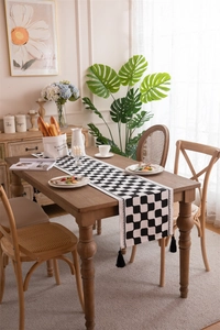 Close-up of black and white checkered table runner with elegant tassels on a wood table
