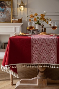 Detalle de mantel jacquard rojo con patrones geométricos blancos y flecos finos