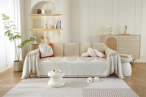 Gros plan sur la housse de canapé en chenille beige avec motifs d'arches et franges