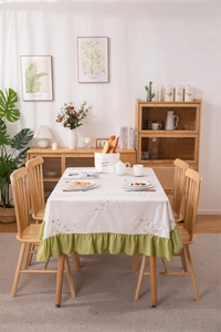 Detail of floral embroidery and green ruffled edge on a cotton linen tablecloth