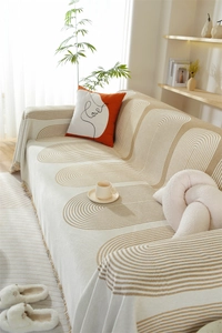 Texture détaillée du couvre-canapé en chenille beige avec motifs géométriques et franges