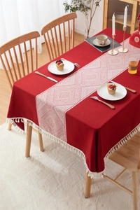 Detalle de mantel de jacquard rojo con motivos geométricos blancos y adornos de borlas