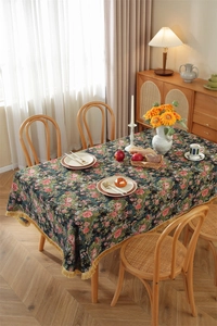 Detailed view of vintage floral tablecloth featuring red roses and golden tassels