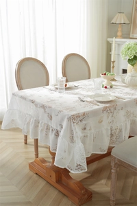 Détail de la nappe en dentelle blanche française avec motifs floraux et bords volantés