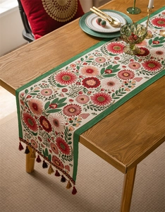 Detailed view of floral jacquard table runner with red dahlias and colorful tassels