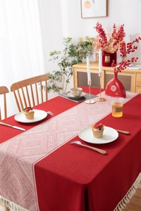 Detalle del mantel de jacquard rojo festivo con borlas blancas y patrones geométricos