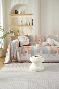 Detail of Chenille sofa cover featuring orange stars, vertical stripes, and fringe edges
