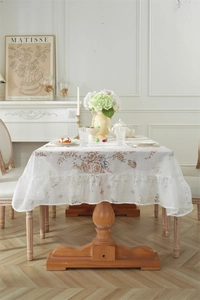 Détail de la nappe en dentelle à fleurs et papillons avec élégant bord à volants