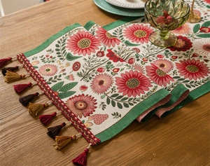 Close-up of floral jacquard table runner with colorful tassels on a wooden dining table