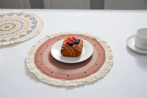 Gros plan d'un set de table bohème rond avec motifs brique et pompons de couleur crème