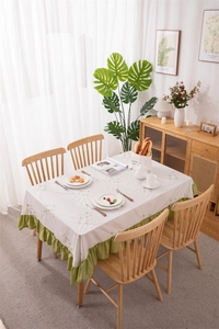 Detail of floral embroidery on cream cotton tablecloth with green ruffled edges