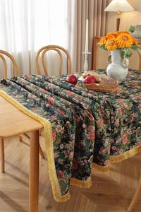 Detail of dark green floral table cloth with golden fringe and retro flower pattern