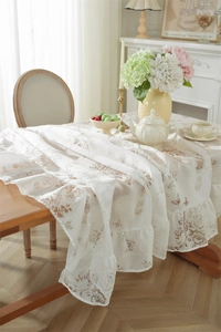 Détail d'une nappe en dentelle crème avec imprimé rose vintage et bord à volants