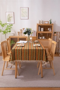 Bohemian orange and green striped tablecloth detail with creamy cotton tassels edge