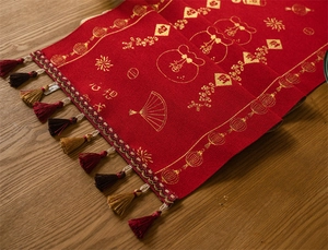 Detail of red Chinese New Year table runner with gold lantern patterns and festive tassels