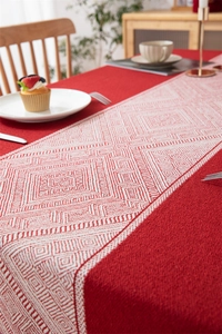 Detalle de mantel festivo de jacquard rojo con motivos geométricos y detalles de borlas