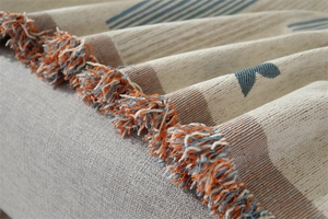 Detail showing Nordic chenille throw blanket with blue orange tassels and woven texture