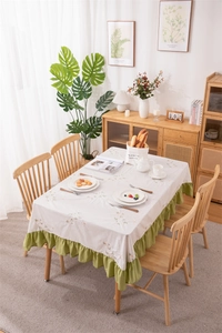 Detailed embroidery on ivory tablecloth with vibrant green ruffle trim edges