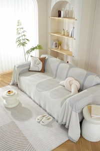 Détail d'un jeté de canapé en chenille nordique avec motifs crème et franges