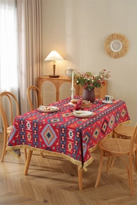 Detail of red jacquard tablecloth with geometric patterns and golden fringe tassels
