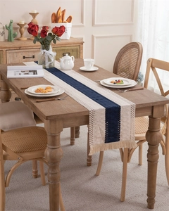 Detail of woven table runner featuring navy stripes and cream fringes on a wooden table
