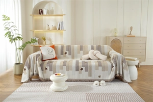 Detail of chenille sofa cover showing beige fabric with star patterns and tassel edges