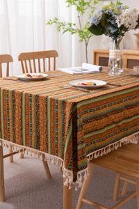 Detail view of ethnic bohemian tablecloth featuring vertical stripes and white cotton tassels