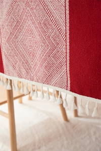 Primer plano de mantel jacquard rojo con patrones de diamantes y flecos blancos
