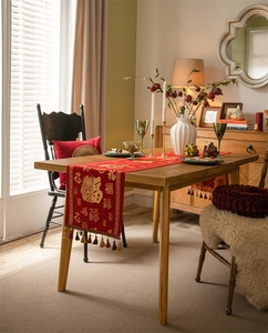 Detail of red festive table runner with golden Fu character and elegant fringe tassels