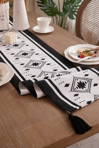 Detail of woven table runner with black geometric patterns and handmade fringes