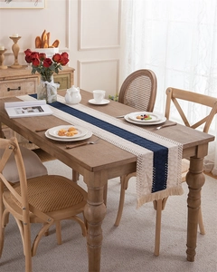 Detail of woven table runner with blue diamond patterns and boho tassels on a wood table