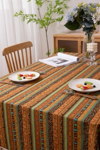 Detail of bohemian striped tablecloth with geometric patterns and white fringe tassels