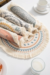 Détails macro des sets de table ronds bohèmes avec motifs ethniques et pompons à franges