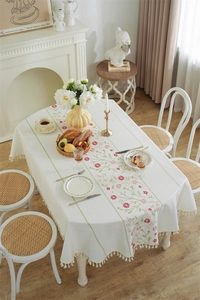 Detail of white jacquard tablecloth with floral embroidery and handmade fringe edges