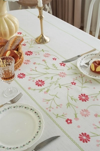 Detailed embroidery of floral patterns on a rustic beige tablecloth with green borders