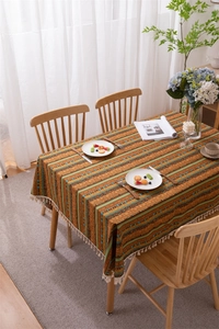 Detail of bohemian striped tablecloth with warm ethnic patterns and white tassel fringe