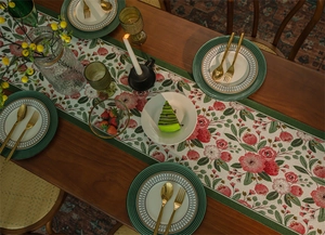 Dettaglio runner da tavola jacquard con fiori rossi e bordo verde su legno scuro