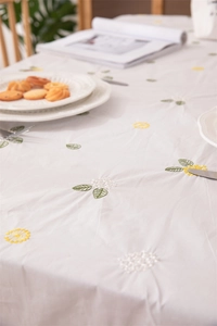 Close-up of spring cotton tablecloth featuring delicate floral embroidery and ruffled edges