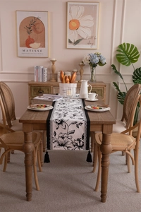 Detail of checkered jacquard table runner with black vintage floral patterns and tassels