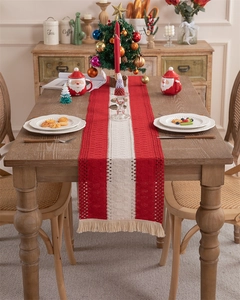 Detail of red and cream woven table runner with tassels in a cozy Christmas table setting