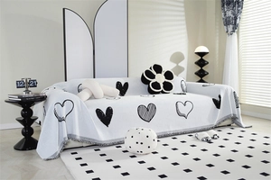 Detail of white chenille sofa cover featuring black heart patterns and tasseled edges